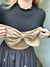 Minimalismo y estilo se encuentran en este crop top de líneas limpias, realzado por un lazo maxi que aporta un aire romántico y contemporáneo. Perfecto para combinar con faldas y pantalones de tiro alto.
